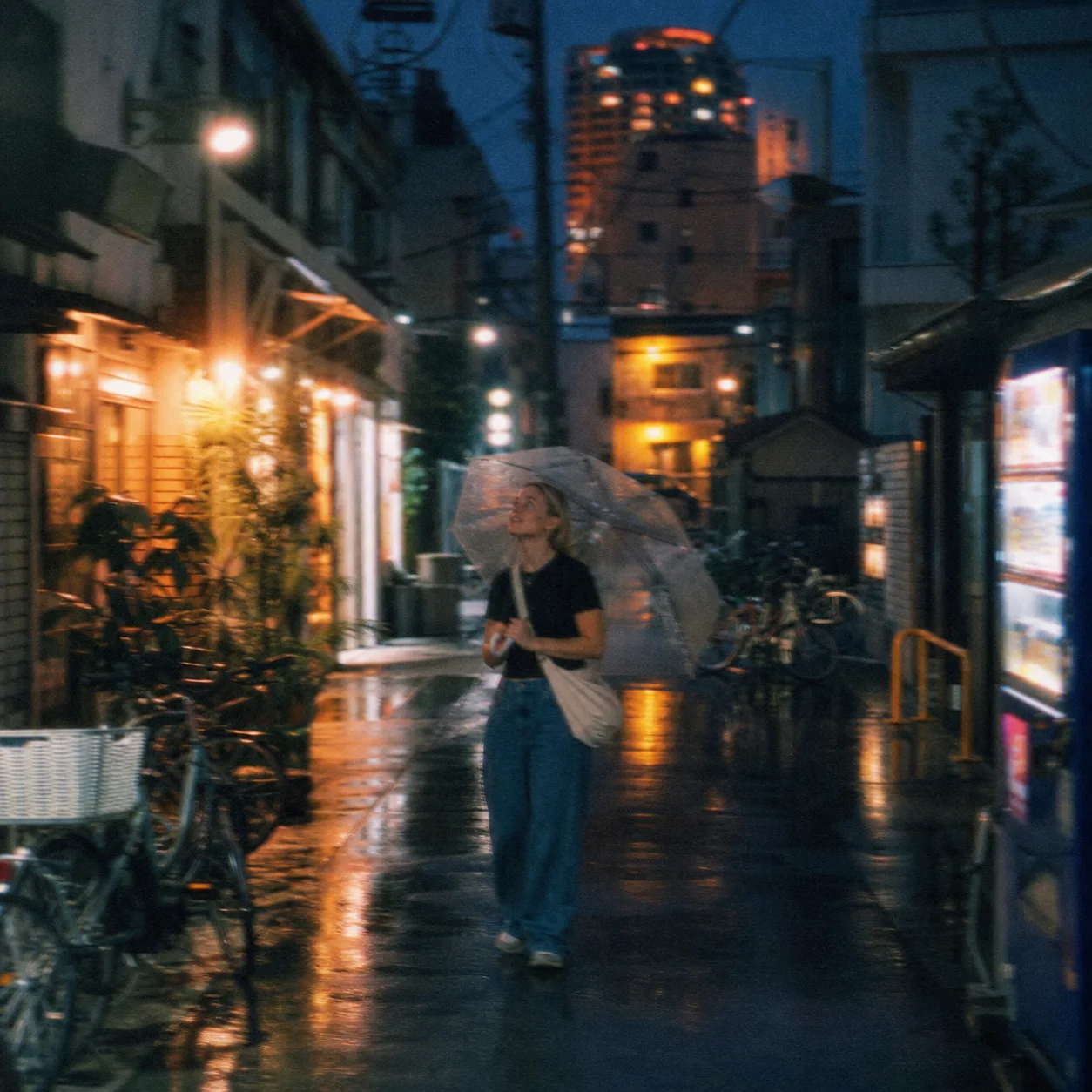 Traveler exploring a rain-softened city street at dusk