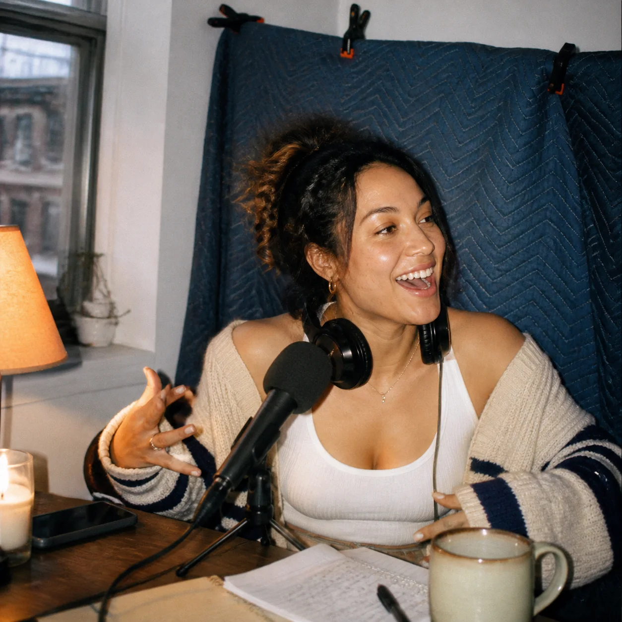Podcaster laughing in a small apartment recording corner